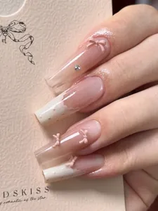 Close-up of handmade press-on nails with delicate 3D pink bows and rhinestone accents