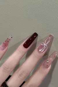 Close-up of cat-eye press-on nails with burgundy finish and 3D bow detail