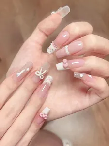 Detailed view of pink and white handmade press-on nails with bow and heart accents