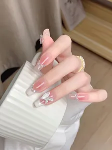 Close-up of elegant press-on nails with butterfly charms and pearl rhinestone detail