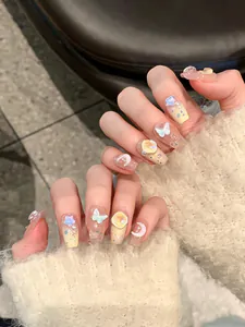 Close-up detail of decorative press-on nails with 3D butterfly and star designs