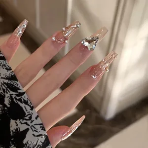 Close-up of elegant long coffin press-on nails with heart crystal and pearls.