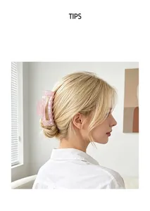 Detailed side view of a large iridescent pink shark hair claw clip worn on a blonde hair bun