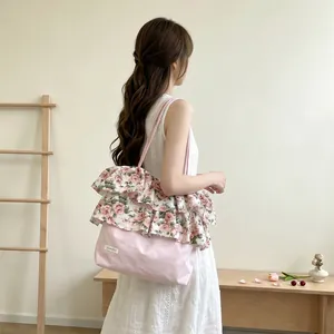 Detailweergave van de roze vintage tas met rozenmotief en ruches gedragen door een model