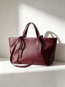 Bolso tote de cuero suave burdeos bajo luz arquitectónica minimalista