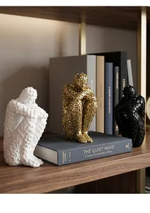 Macro view of three abstract mosaic character sculptures in white gold and black on bookshelf