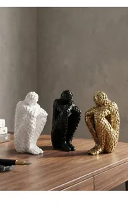 Detailed view of three mosaic abstract thinker statues in gold, black, and white on a desk