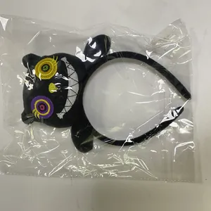 Black Halloween plush monster headband with colorful embroidery details in clear plastic packaging