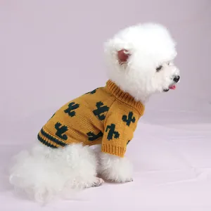 Vista lateral de un perro blanco con un suéter de punto amarillo con patrones de cactus