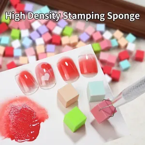 Detailed macro view of 1cm mini cube sponges for gradient nail art with metal claw tool