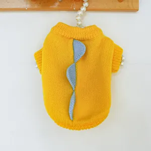 Detalle de un suéter amarillo de punto para mascotas con diseño de aletas de dinosaurio