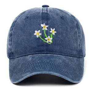 Vooraanzicht van een denim baseballpet met fijn wit geborduurde bloemen op de voorkant.
