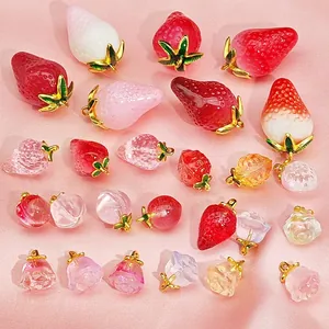 A detailed macro view showing assorted resin strawberry and peach charms for DIY jewelry.