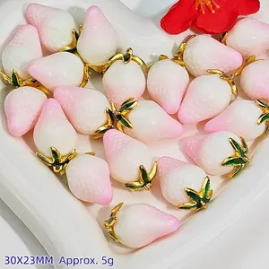 Detailed close-up of pink and white peach strawberry pendants in heart-shaped dish