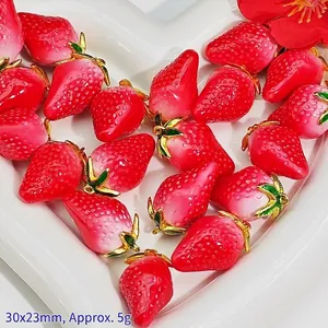 Detailed view of red strawberry pendants with gold leaf caps and 30x23mm size label