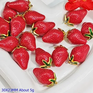Detailed view of red strawberry pendants with gold leaf accents for DIY jewelry making