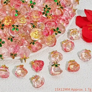 Detailed view of pink crystal peach charms with green leaves for DIY jewelry making.