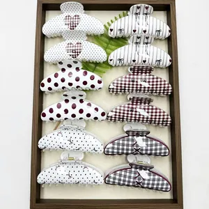 Variety of patterned hair claw clips with polka dots and hearts in a display tray.