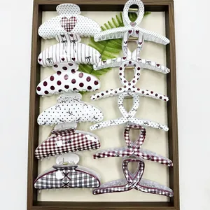 Close-up detail of various patterned hair claw clips featuring polka dots and grids.
