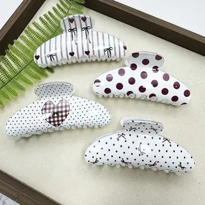 Detail view of four stylish patterned hair claw clips with heart and polka dot designs