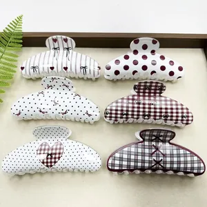 Macro view of six stylish Korean hair claw clips with varied patterns in a tray.