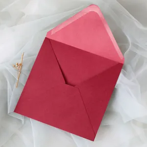 Vue détaillée d'une enveloppe en papier nacré bordeaux pour invitations sur tulle blanc