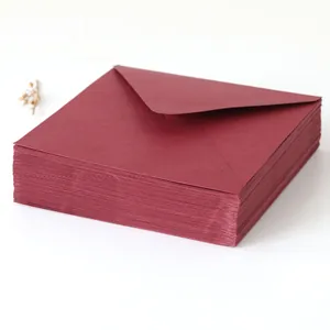 Pile d'élégantes enveloppes en papier perlé rouge vin pour invitations de mariage