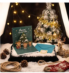 Detailed view of a 3D pop-up Christmas card with reindeer and tree on snowy ground.
