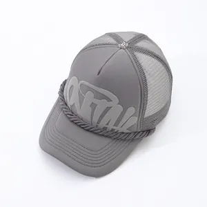 Close-up detail of grey street fashion trucker hat featuring puff-print letters and mesh back