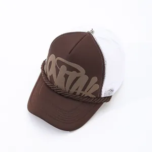 Close-up of brown trucker hat with white mesh and graffiti-style print detail.