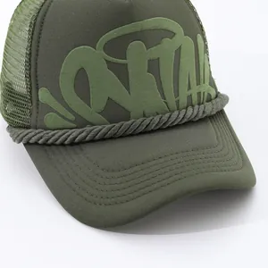 Close-up detail of army green trucker hat showing embossed puffy graffiti print and mesh
