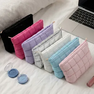 Stijlvolle gewatteerde make-up tassen in diverse kleuren op een wit bed