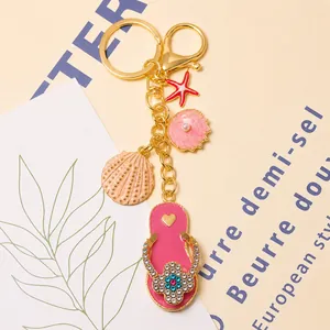 Detail van gouden strand sleutelhanger met strass slipper, schelp- en zeester hangers.