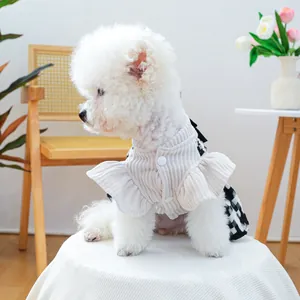Détail d'un chien blanc portant une élégante robe à volants côtelée et jupe à carreaux