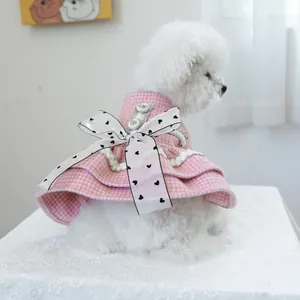 Gros plan d'une robe pour animal en tweed rose avec un grand nœud à cœurs