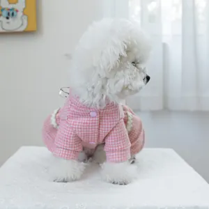 Gros plan d'une robe rose à carreaux pour animaux avec boutons sur un petit chien