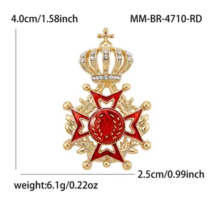 Detail view of an ornate crown brooch with red enamel and rhinestones on gold alloy