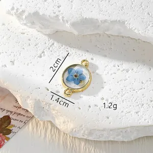Detailansicht eines blauen Vergissmeinnicht Trockenblumen Harzanhängers mit Goldlegierung