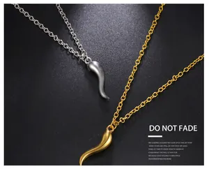 Detail shot of matte gold and silver chili pendants on a dark textured background.