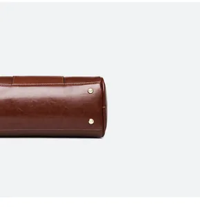 Close-up detail of brown oil leather bag with fine stitching and gold metal feet