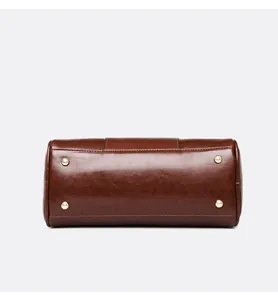 Detailed bottom view of a retro brown oil skin Boston handbag showing gold protective feet