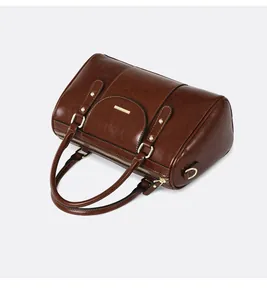 Top view of a vintage brown oil skin Boston pillow bag featuring elegant gold hardware details