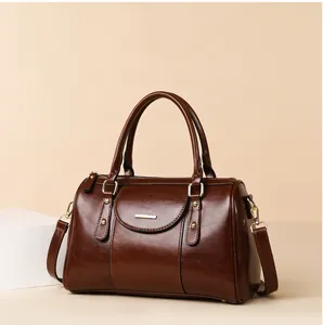 Elegant brown oil leather Boston bag with vintage shoulder strap and gold hardware.