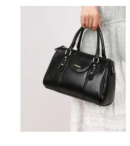 Close-up of elegant black Boston pillow handbag with retro oily leather and gold hardware