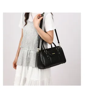 Model carrying a vintage black oil-leather Boston pillow bag with gold hardware