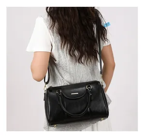 Detail view of retro black oil-skin Boston bag worn as a shoulder bag