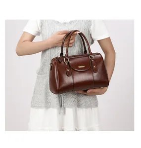 Model holding a retro brown oil leather Boston handbag for size and style reference.