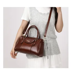 Detailed view of women's vintage brown oil leather Boston bag worn by a model
