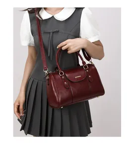 Elegant vintage burgundy oiled leather Boston handbag shown carried by a fashion model