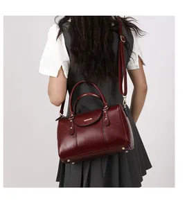 Vintage burgundy oiled leather Boston pillow bag shown on model for size perspective